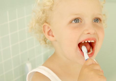 [Translate to Italian:] kid cleaning teeth